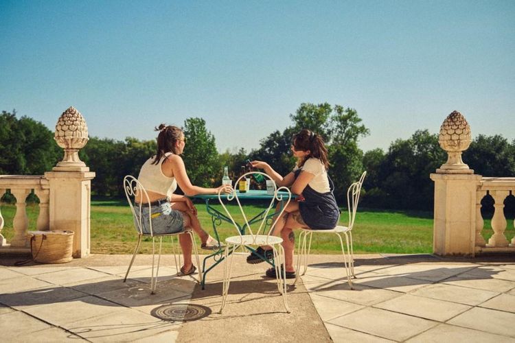 Deux filles du collectif en train de boire un verre sur la terrasse du château de la Testère à Preignan, avec vue sur le parc